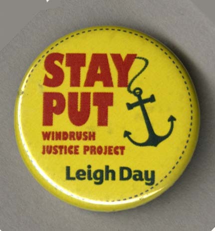 A badge with the slogan 'Stay Put' with an anchor hanging off the letter Y. Underneath the slogan the text 'Windrush Justice Project: Leigh Day' is added. 