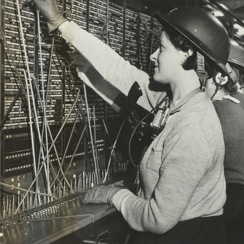 Women telephonists operating a switchboard with steel helmets, 1939-45 (POST 56/14).