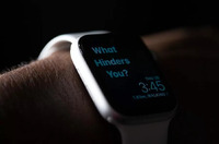 Close-up of a smartwatch on a wrist displaying the text "What Hinders You?"