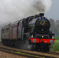 Black and red steam train on tracks.