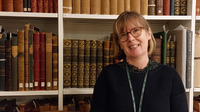 Fiona Davison stands in front of shelves of library books.