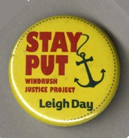 A badge with the slogan 'Stay Put' with an anchor hanging off the letter Y. Underneath the slogan the text 'Windrush Justice Project: Leigh Day' is added. 