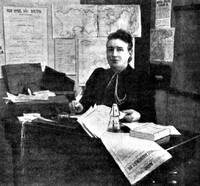 Miss Beeson sat at desk and surrounded by papers.
