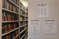 Library book shelves with shelf end signs reading, "B - magic and science" and "FA Astrology and Astronomy". 