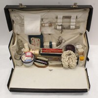 19th century, rectangular nurses case pictured open containing a variety of medical equipment including a baby-weighing net, packaged bandages in different sizes, forceps, syringes, glass tools, thermometers, and more.