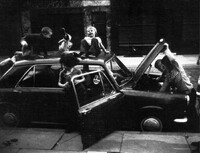 Photograph of children playing in and on a car.