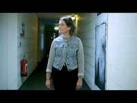 Woman walking down a corridor, with her head turned looking to the side.